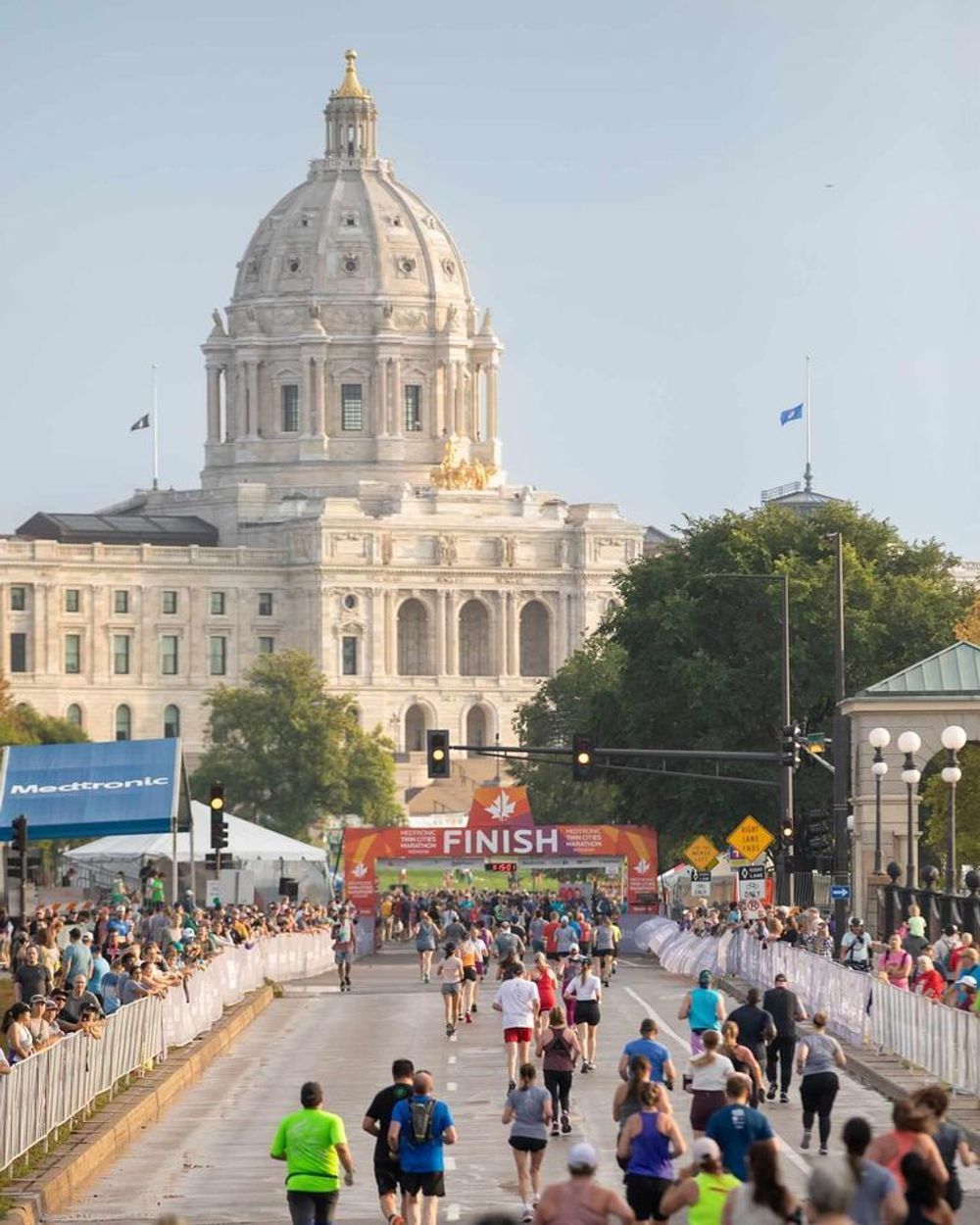 A group of people are running down a street in front of a large building.