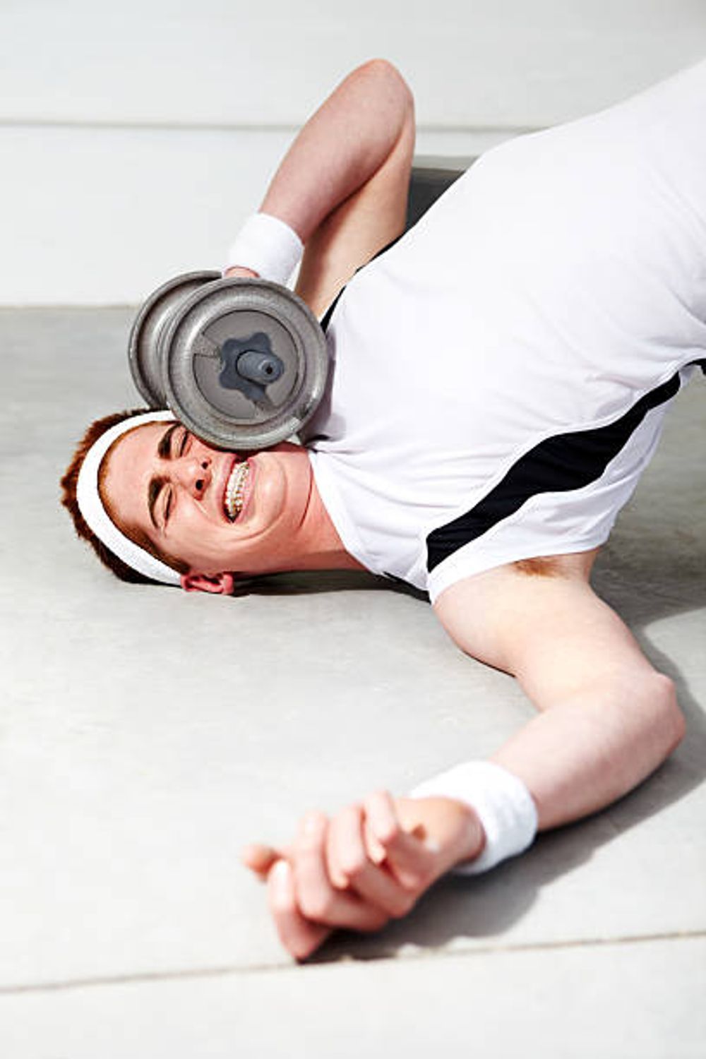 A man is laying on the floor lifting a dumbbell