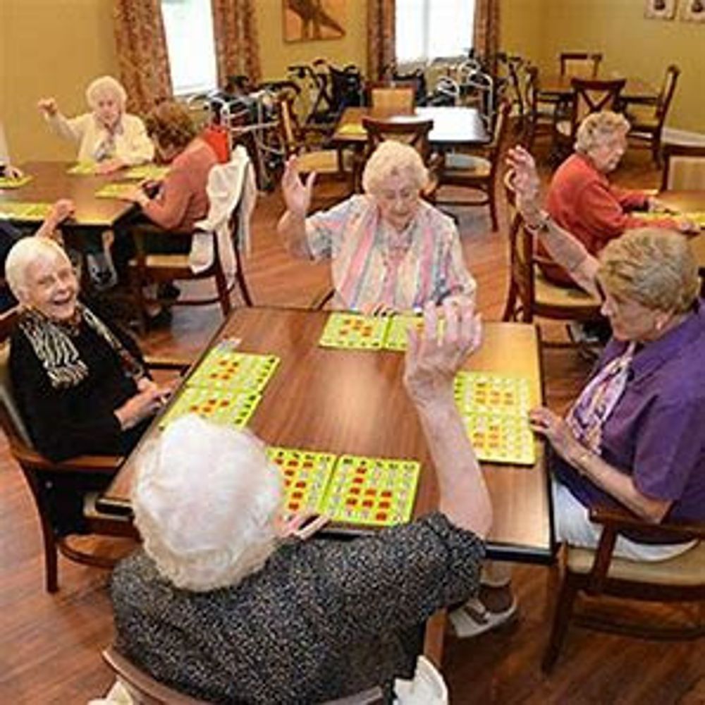 A group of elderly women are sitting at tables playing bingo.