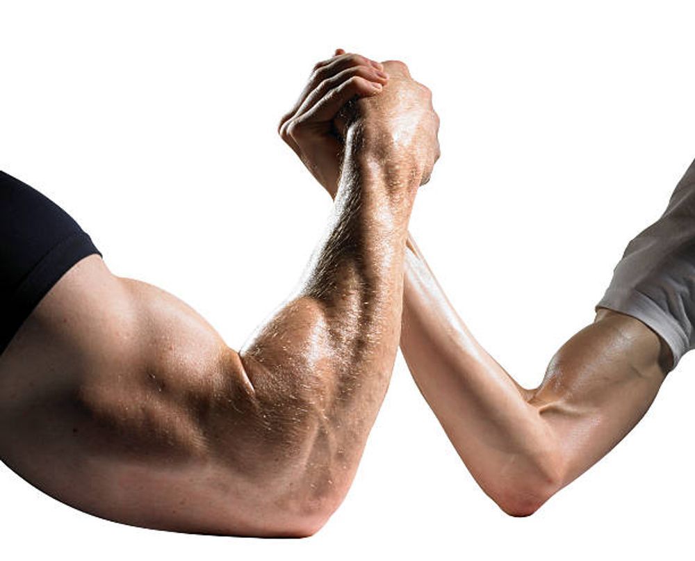 A man and a woman arm wrestling with their arms crossed