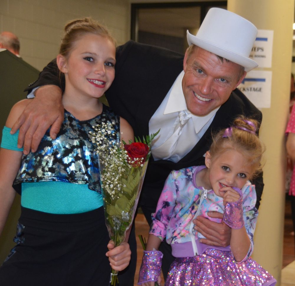 A man in a top hat poses with two little girls