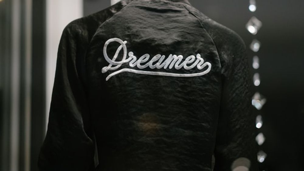 The back of a black jacket with the word dreamer embroidered on it.