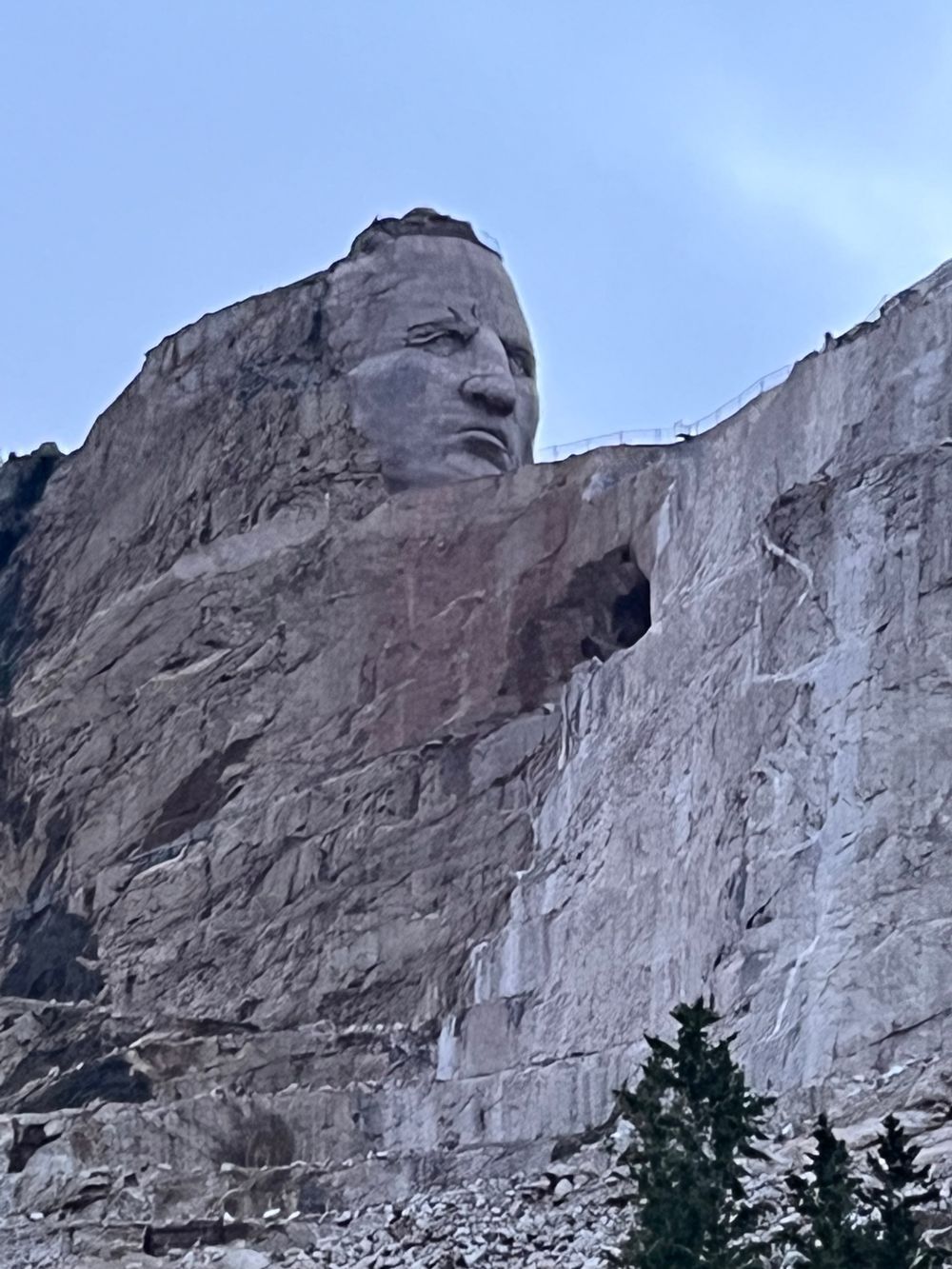 A statue of a man 's face is carved into the side of a mountain.