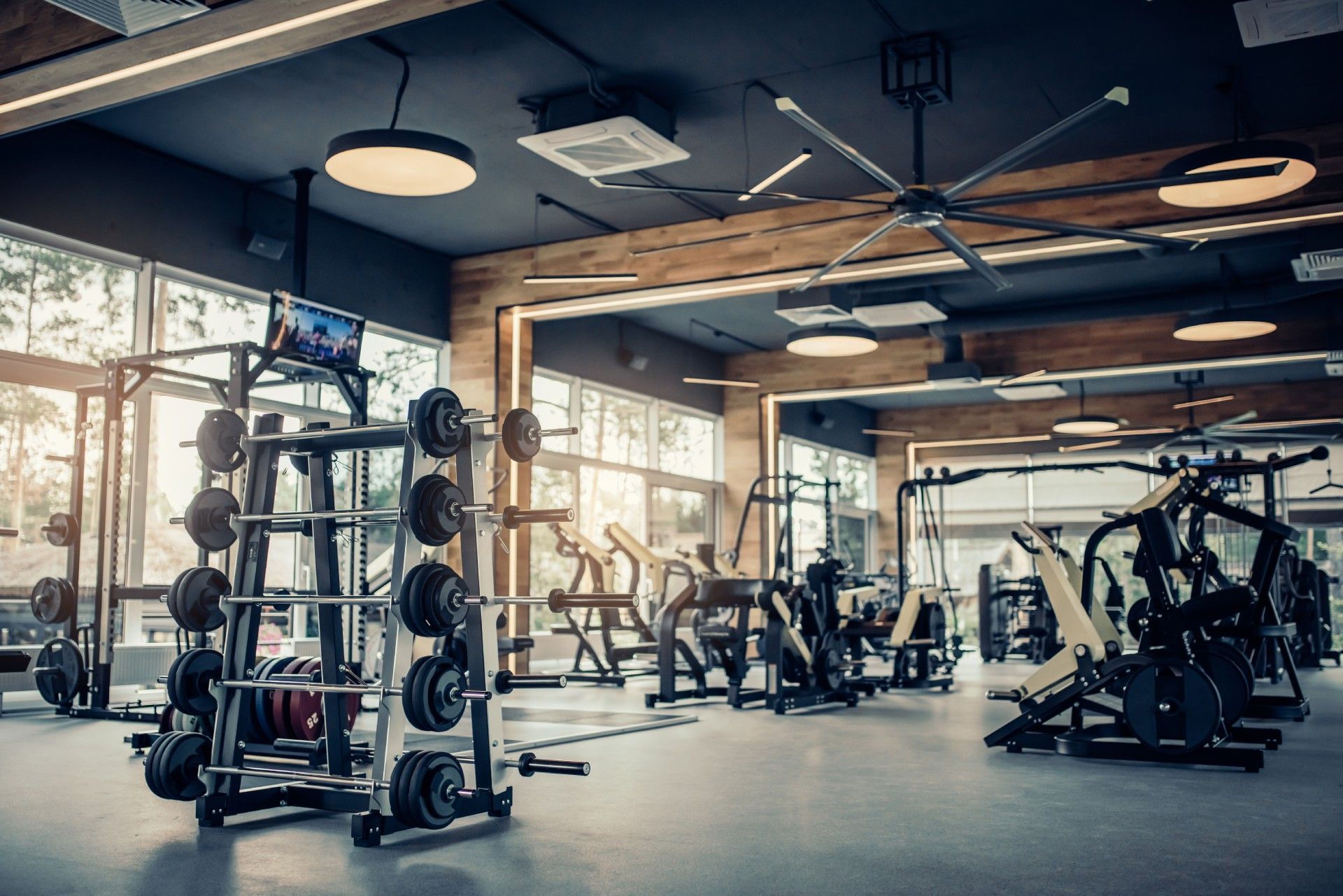 A gym filled with lots of exercise equipment and a ceiling fan.