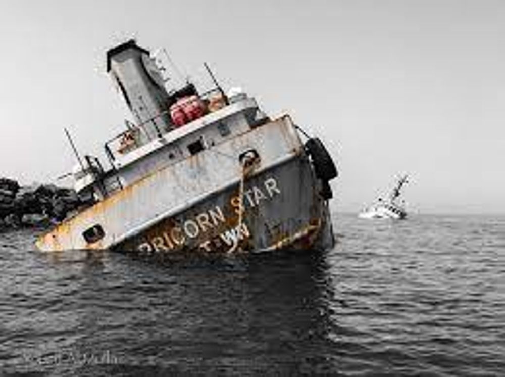 An old rusty ship is floating on its side in the ocean.