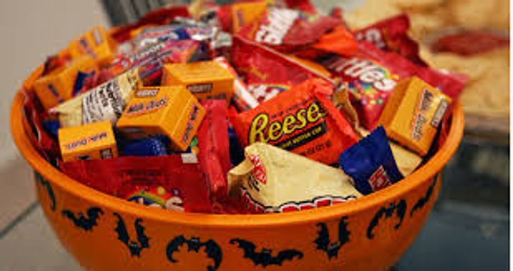 A bowl filled with candy including reese 's and m & m 's.