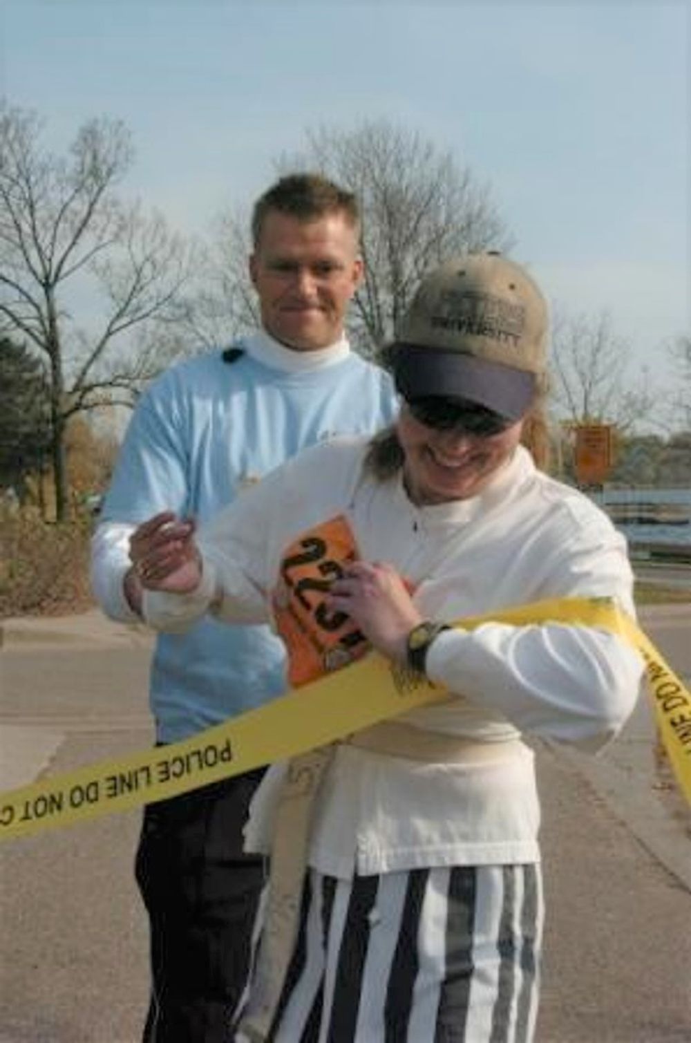 A man and woman are standing next to a yellow tape that says police line do not enter