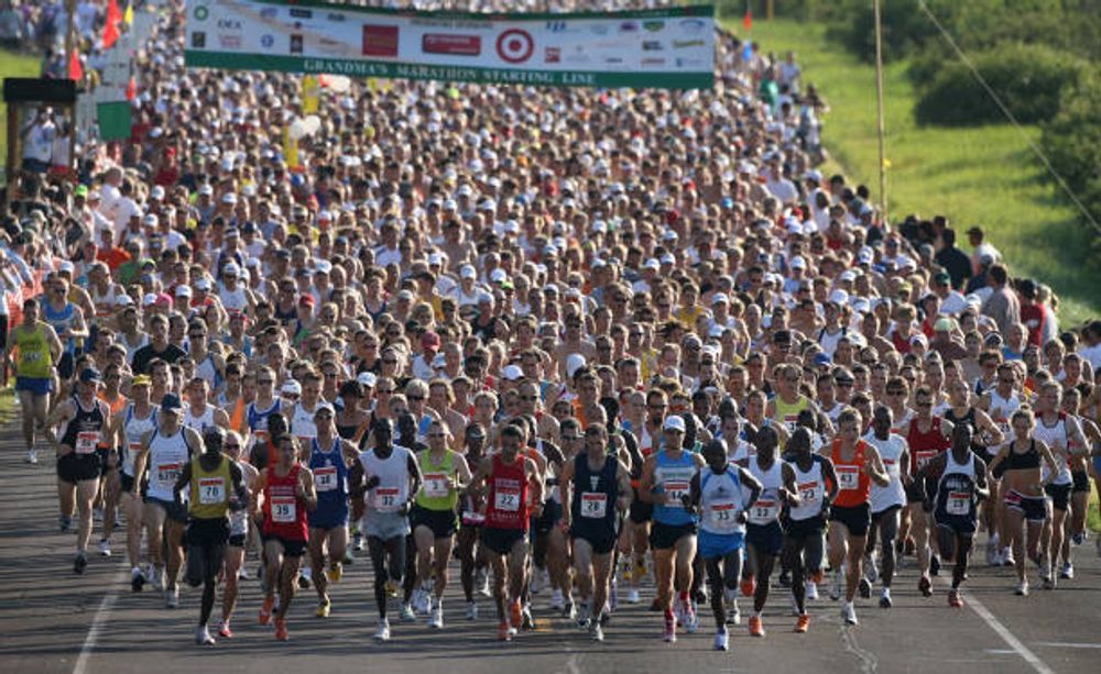 A large crowd of people are running a marathon with a target banner in the background