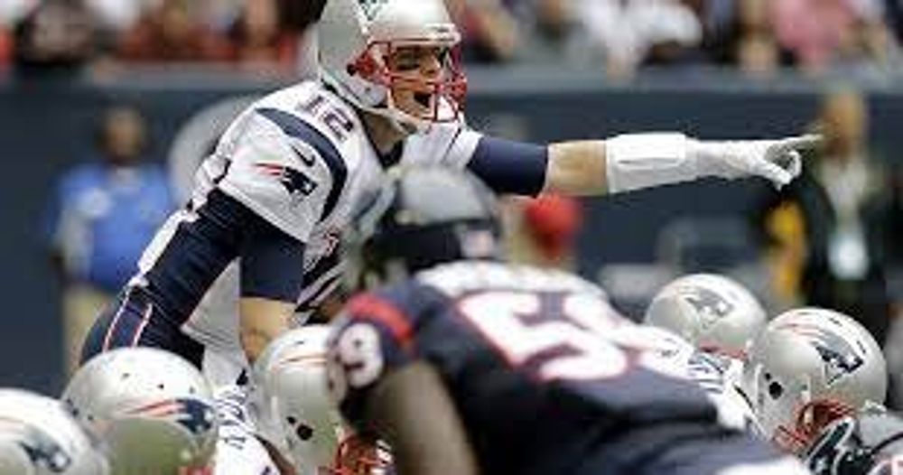 A football player is pointing at a group of players on a field.