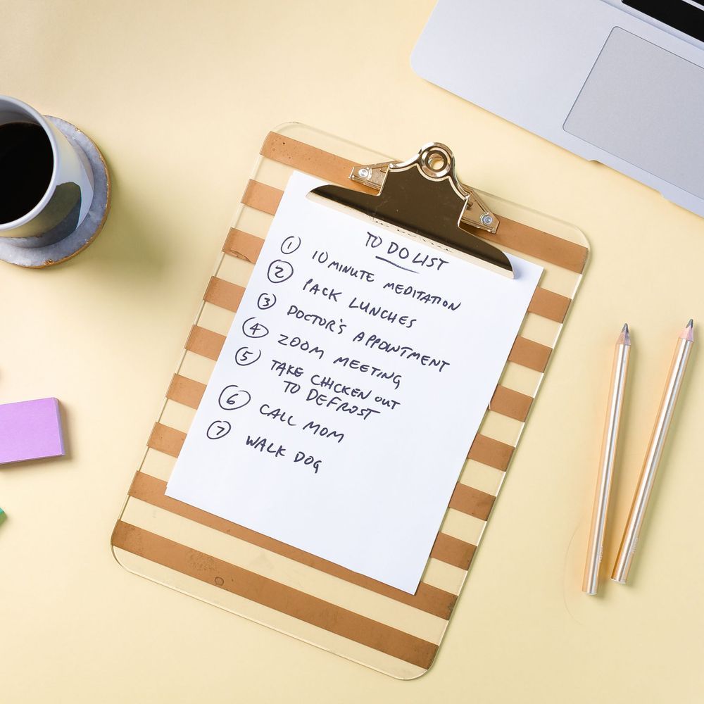 A to do list is on a clipboard next to a cup of coffee and pencils.