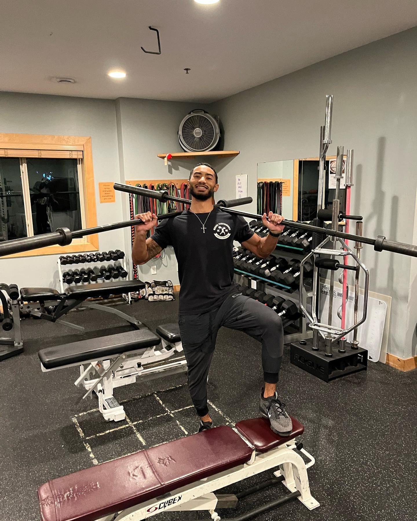 A man is holding a barbell over his head in a gym.