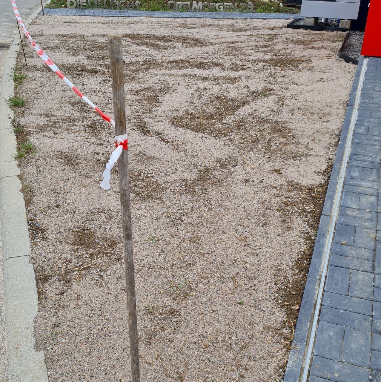 Das Bild zeigt einen unbefestigten, sandigen Bereich, wo Rasen eingepflanzt wurde.