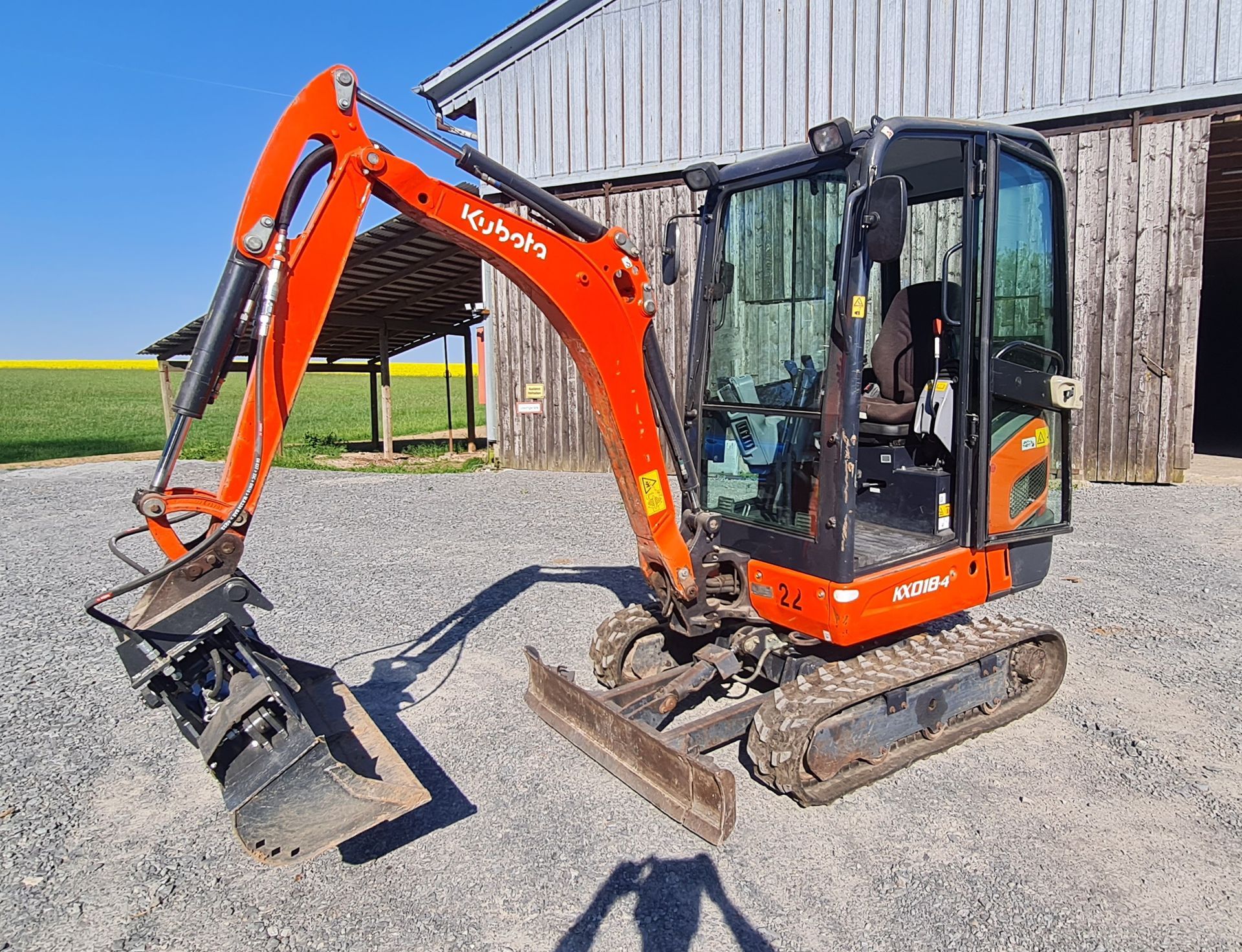 Zu sehen ist ein Minibagger der Erde auf einen Schubkarren lädt.
