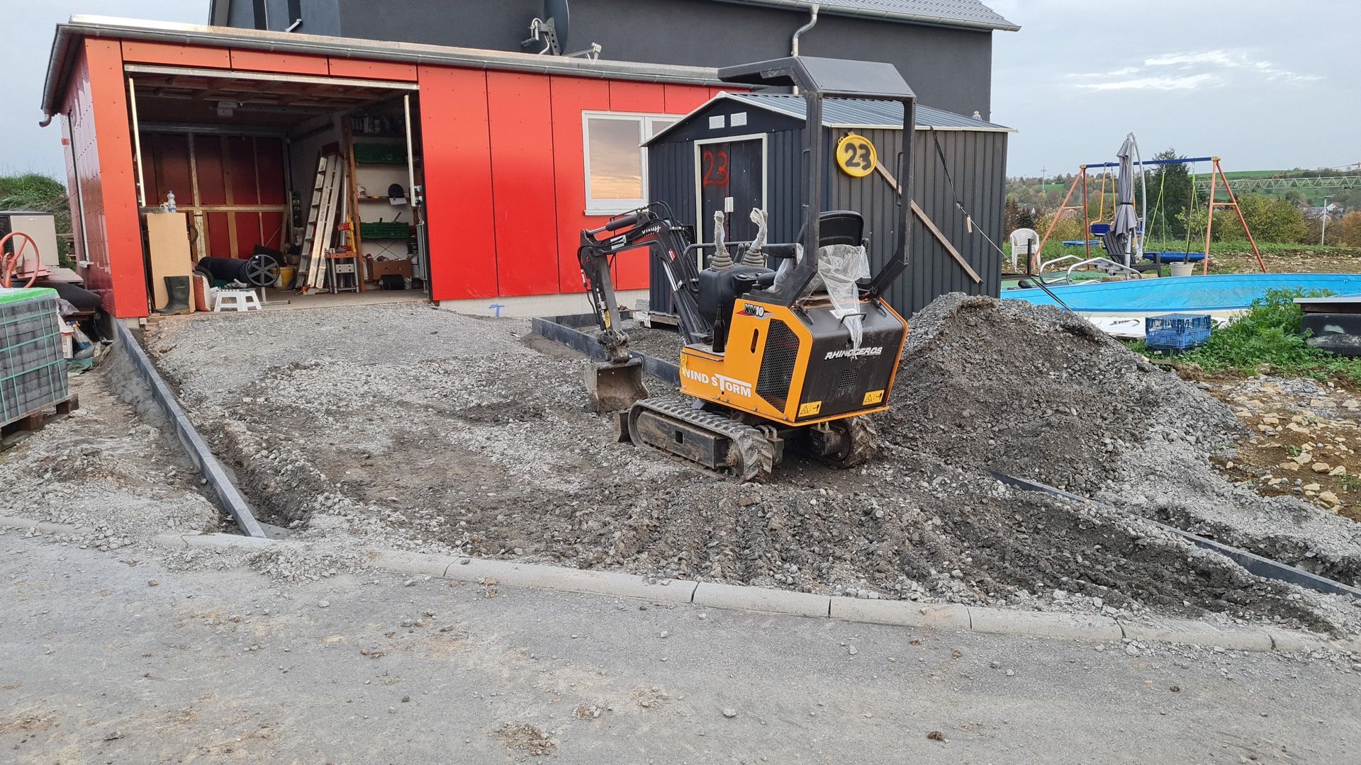Auffahrt zur Garage wird mit einem Minibagger mit Kies befüllt. Die Rabatten sind schon gesetzt
