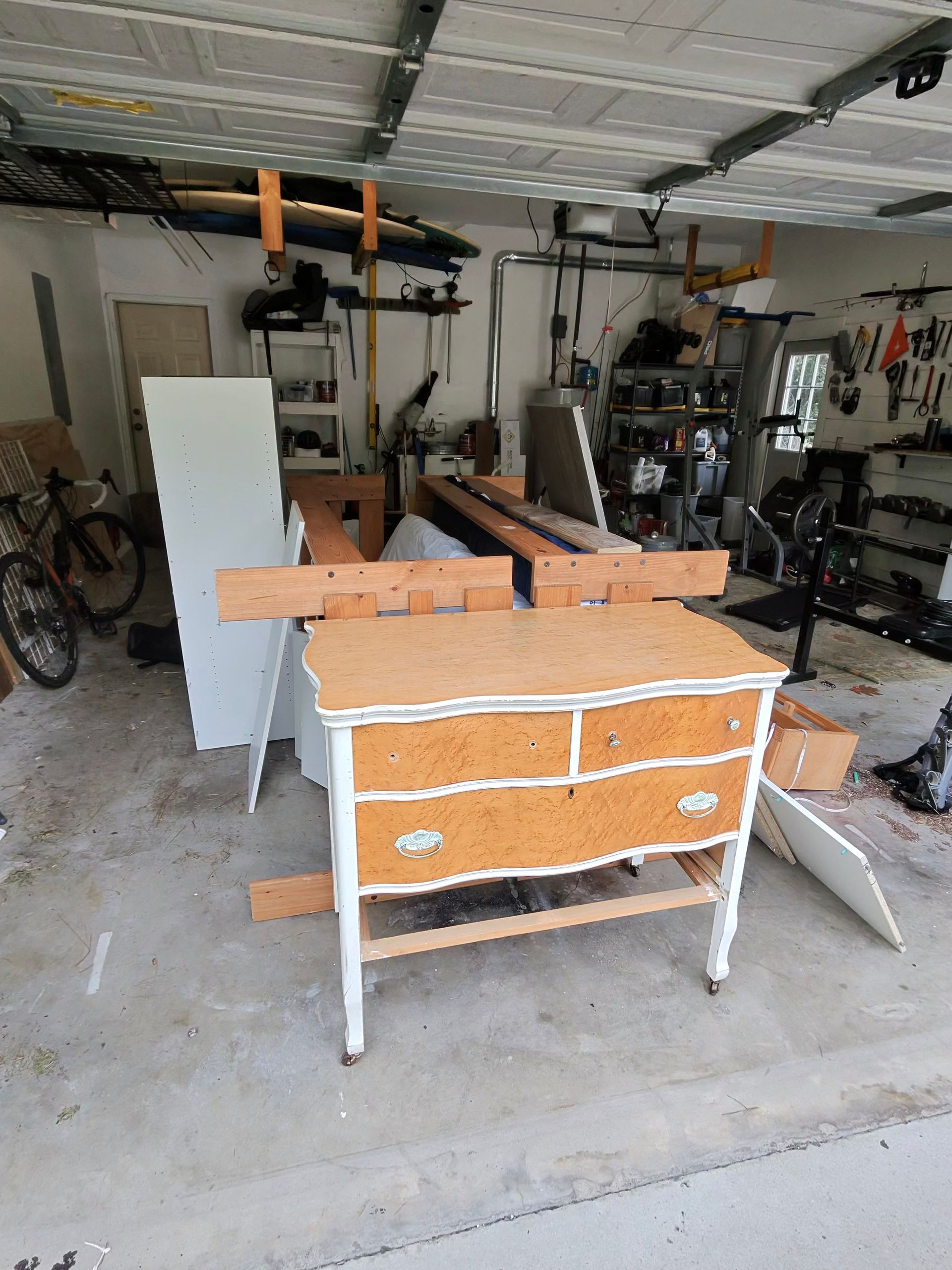 Garage workshop with a workbench, tools, and stored equipment on the concrete floor.