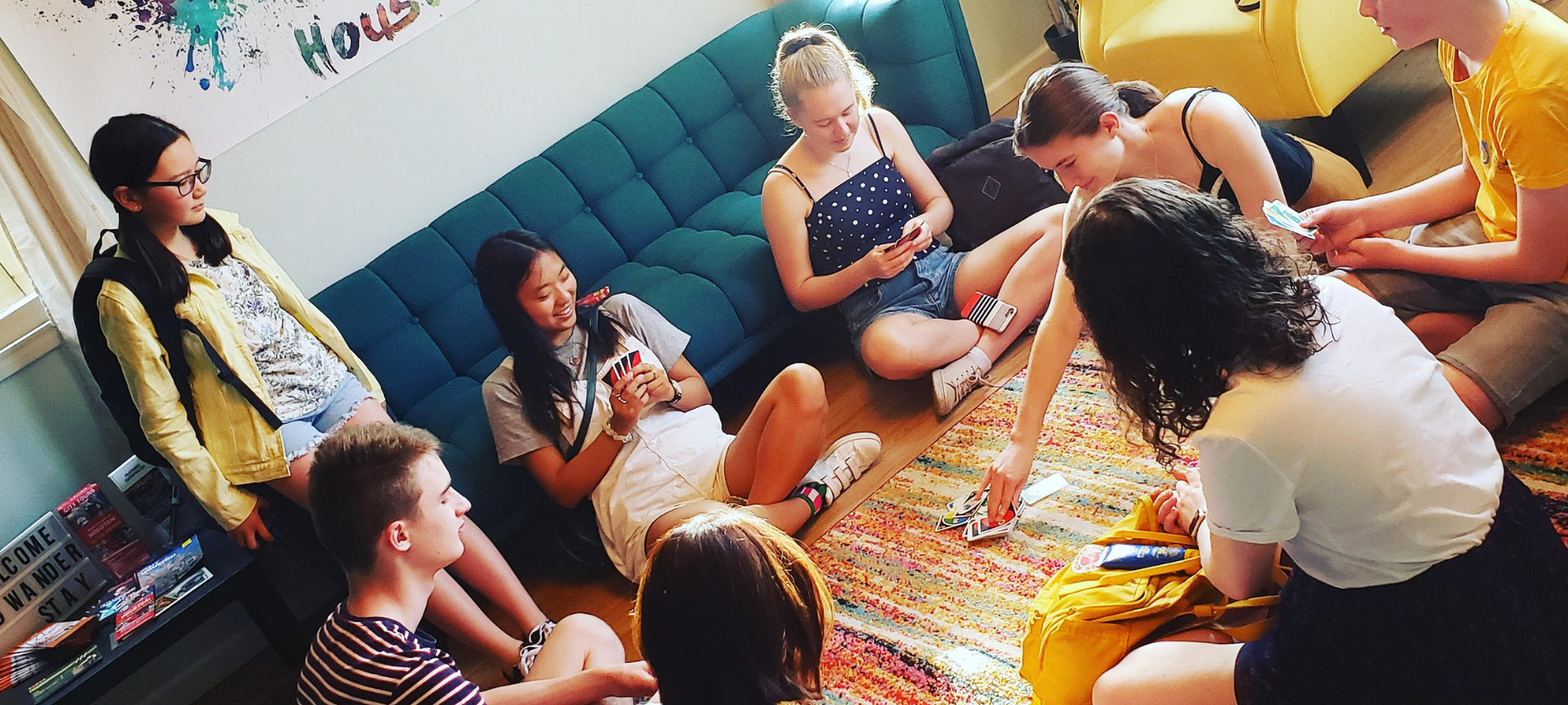 A group of people sitting in a circle playing a card game on a rug.