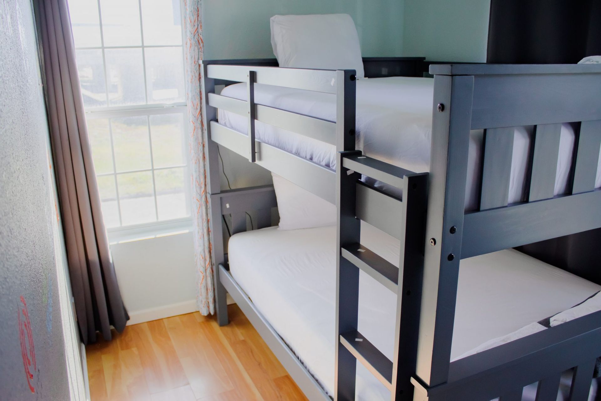 Bunk bed with gray frame in a room with a window and wooden floor.