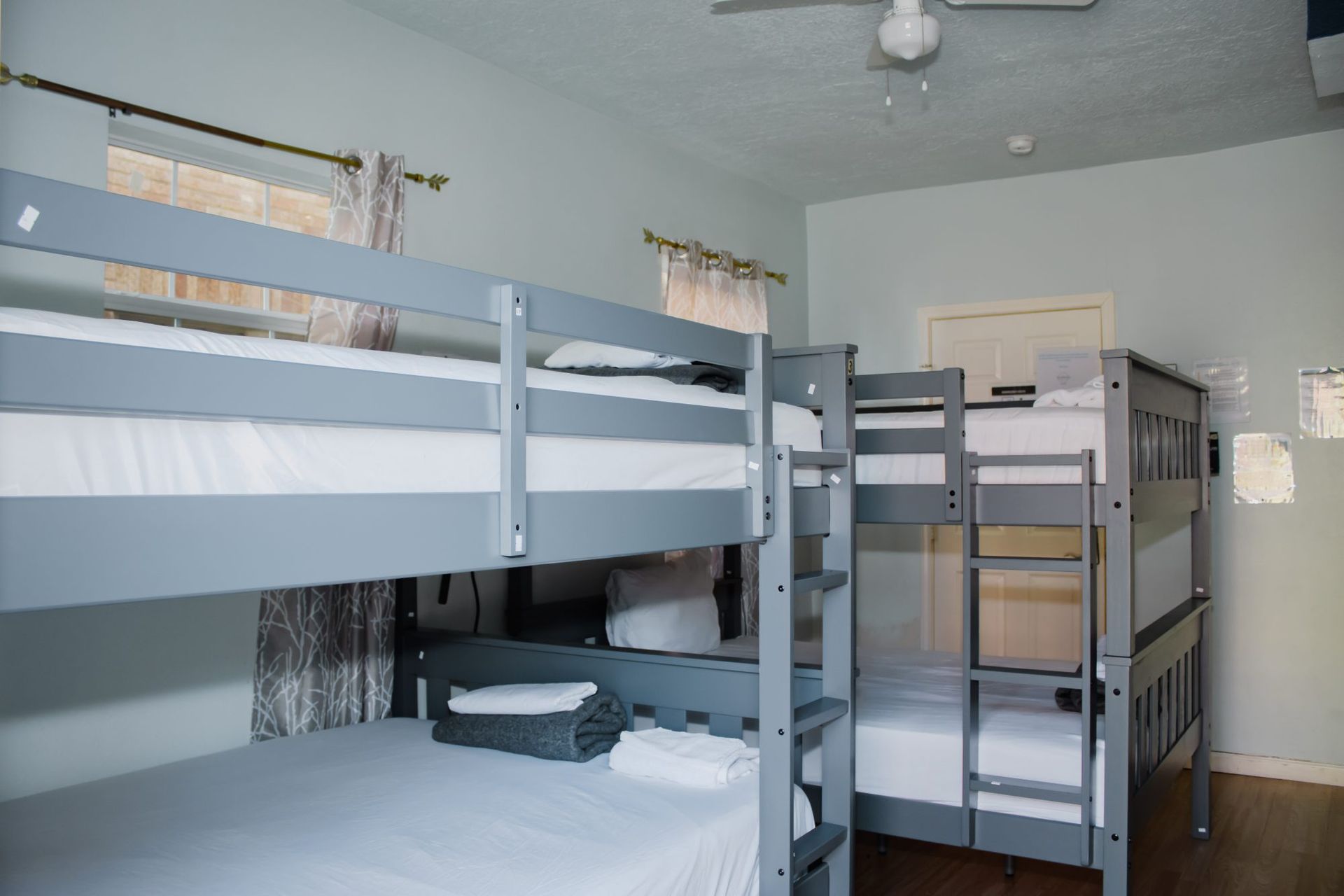Bedroom with multiple gray bunk beds; white bedding.