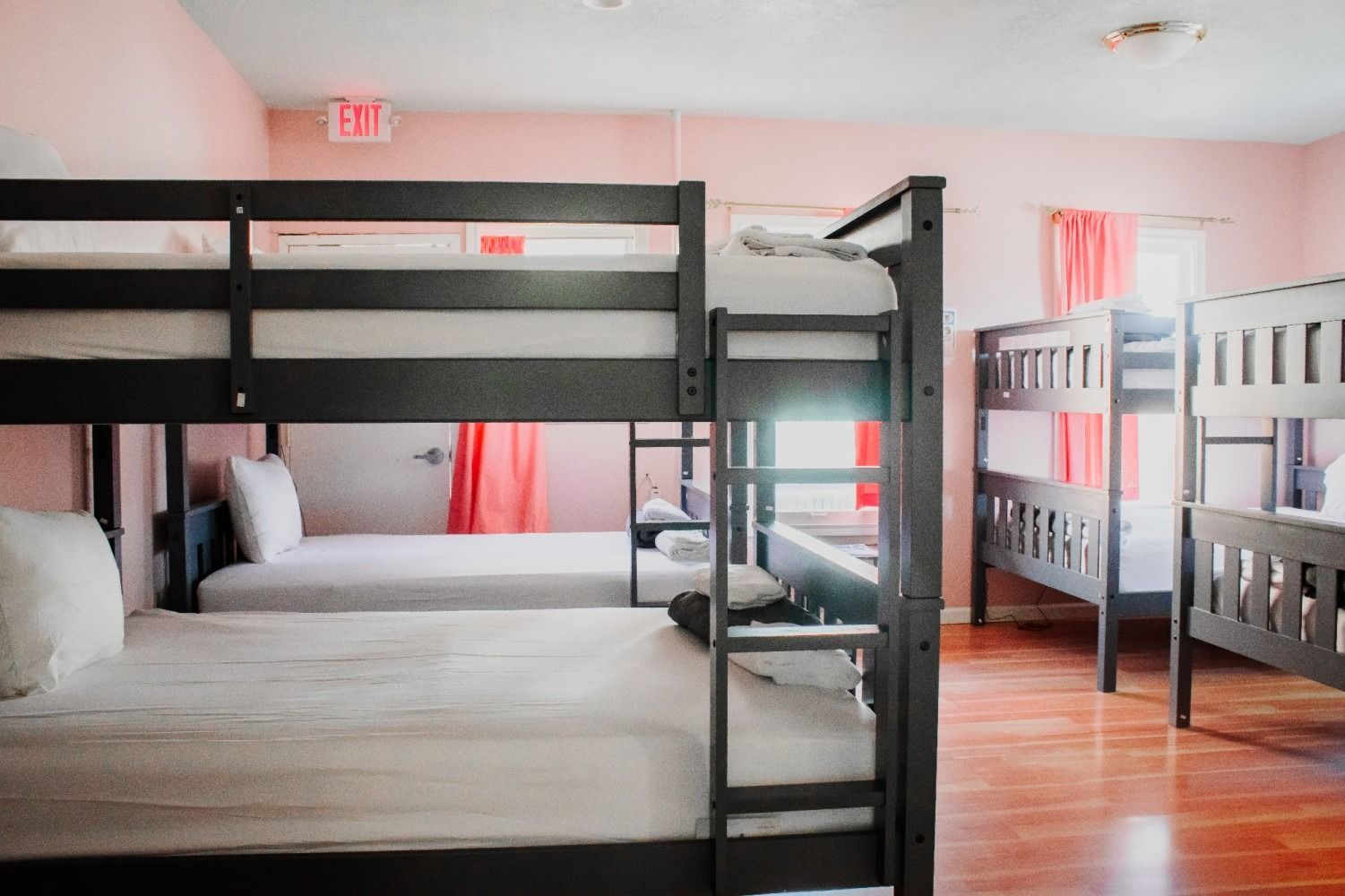 Pink dorm room with bunk beds; hardwood floor, pink walls, and curtains.