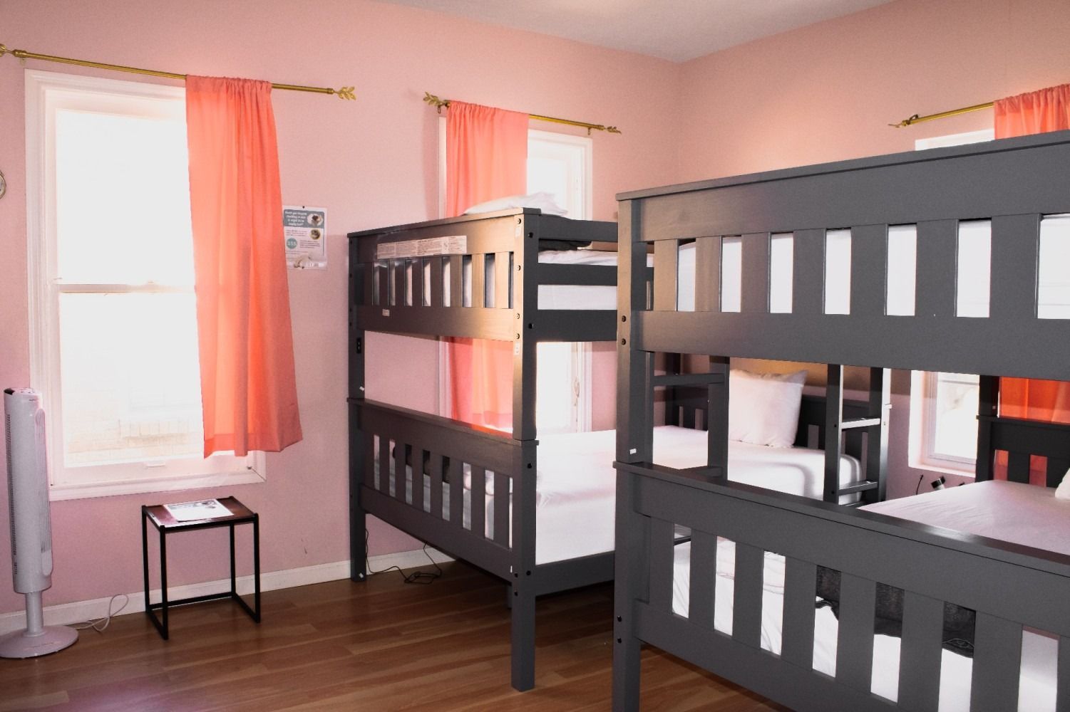 Room with gray bunk beds, pink walls, and coral curtains.
