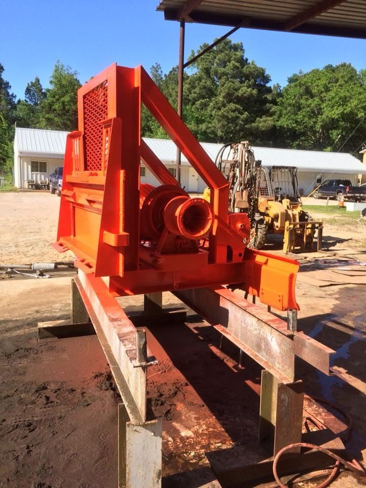 A large orange machine is sitting on a wooden platform