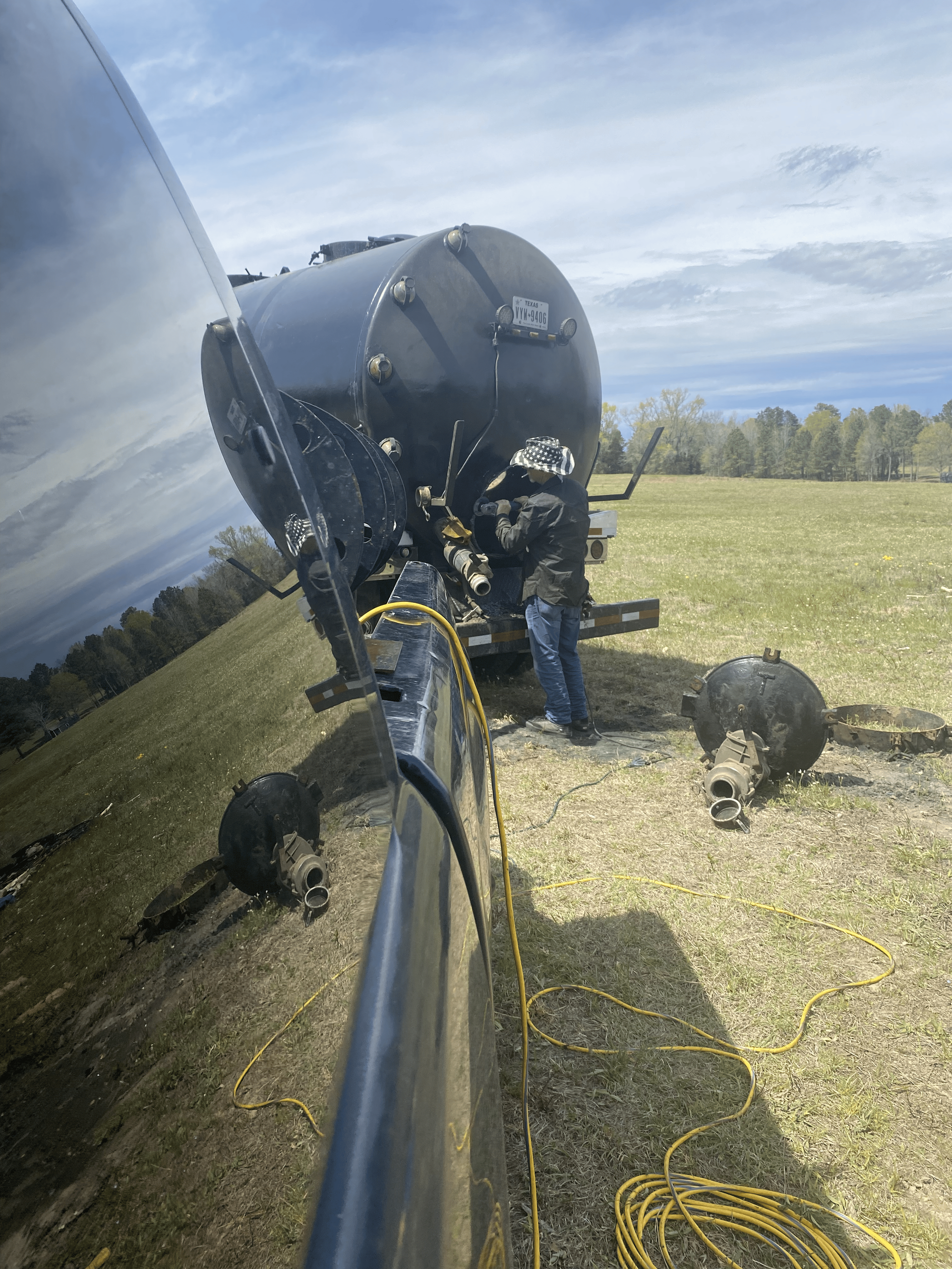A man is working on a boat engine in a field next to a truck.