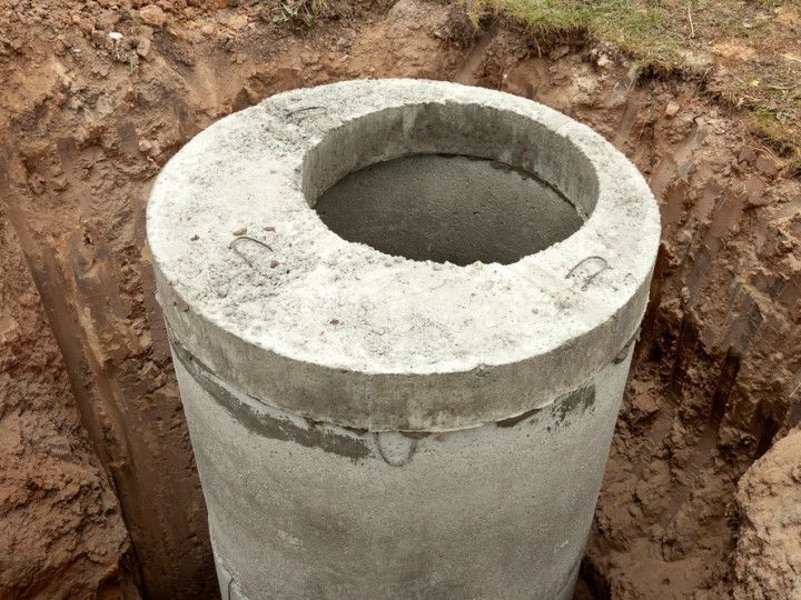 Concrete cylinder with a hole, set in a trench.