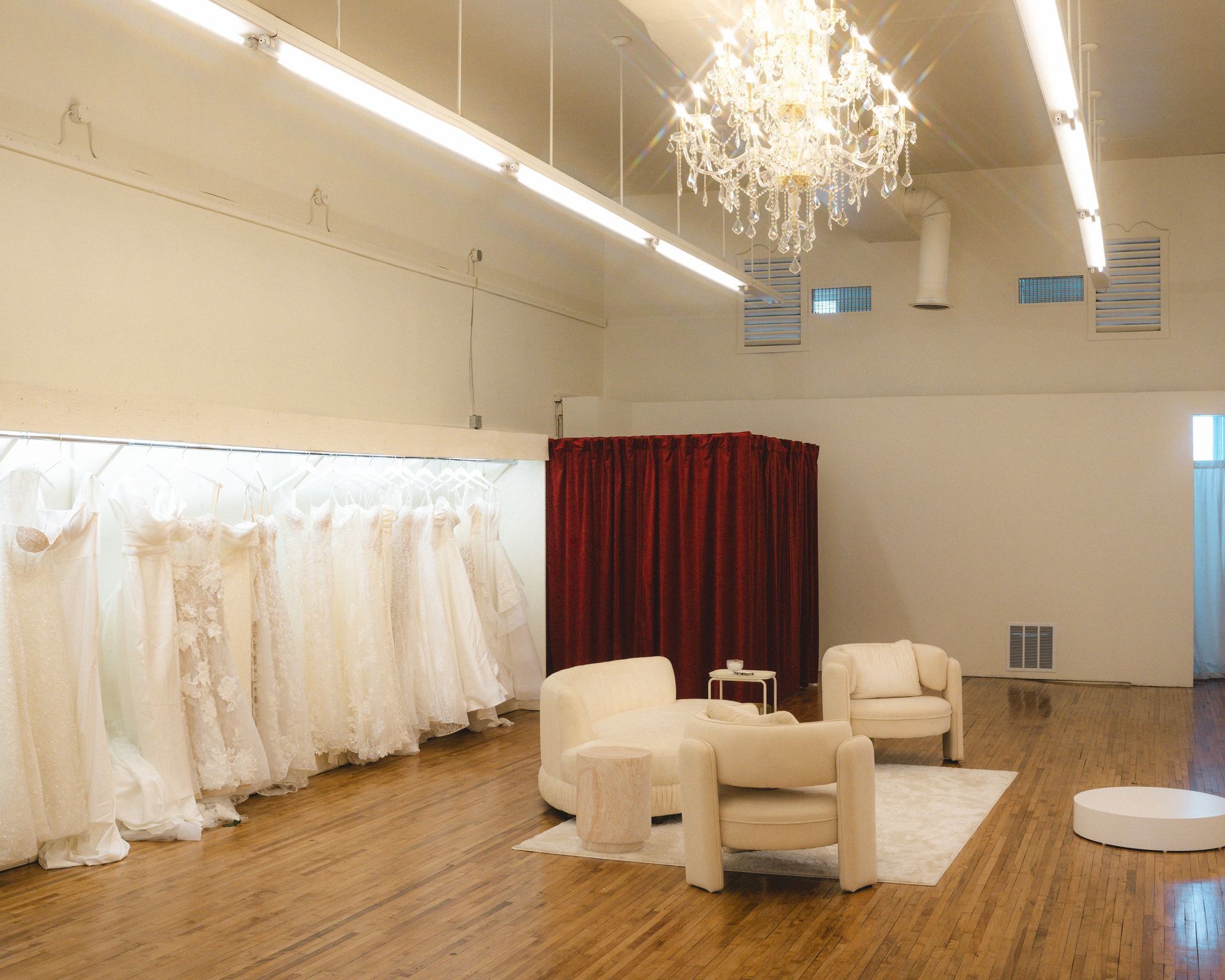 A room filled with lots of white dresses and a chandelier.