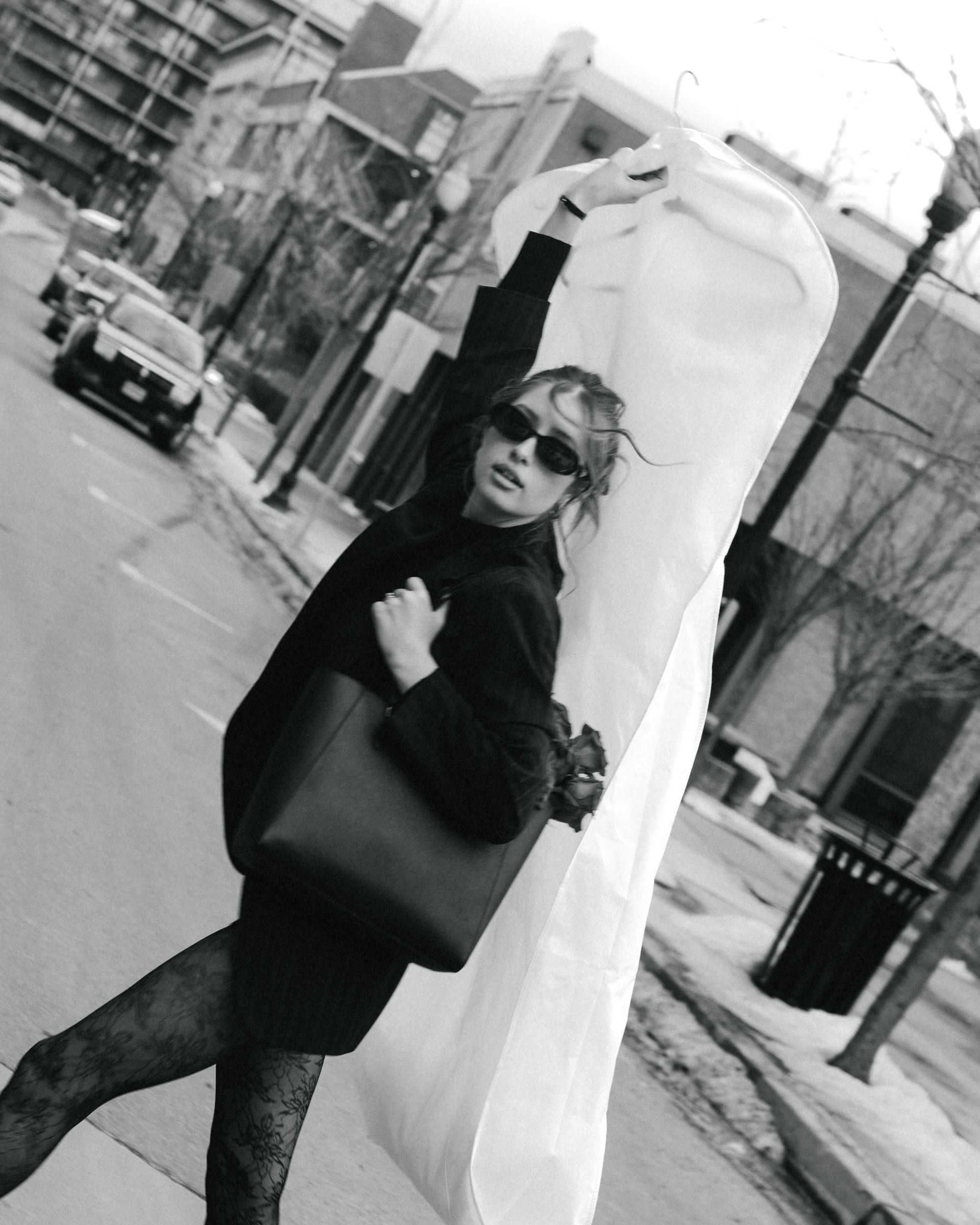A woman is walking down the street carrying a large white bag