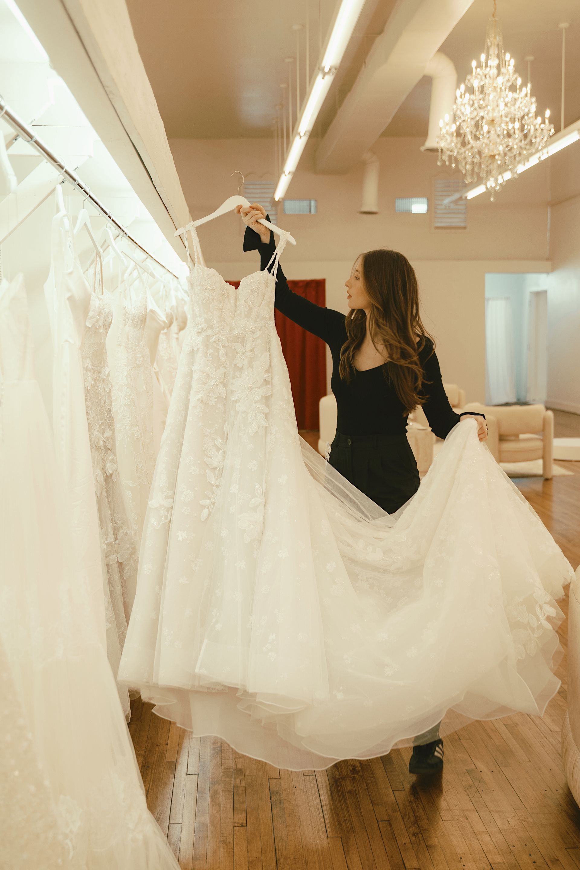 A woman is holding a wedding dress in a bridal shop.