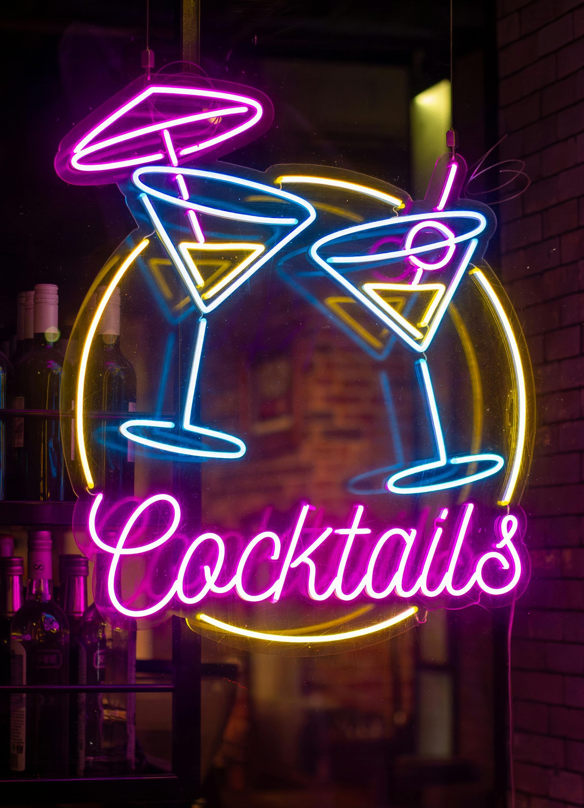 Neon sign advertising cocktails: two martini glasses, umbrella, and 