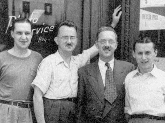 a group of men are posing for a picture in front of a building .
