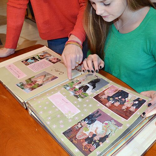 deux femmes sont assises à une table en regardant un album photo .