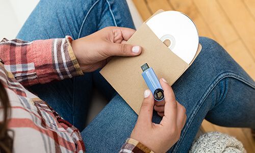 une femme est assise sur le sol tenant un cd et une clé usb .