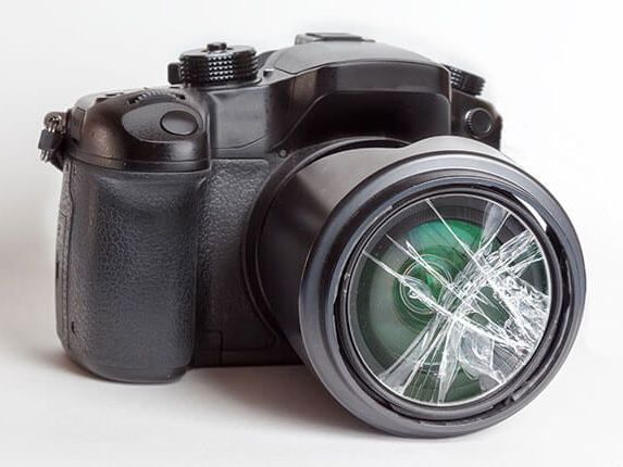 un appareil photo avec un objectif brisé sur fond blanc .