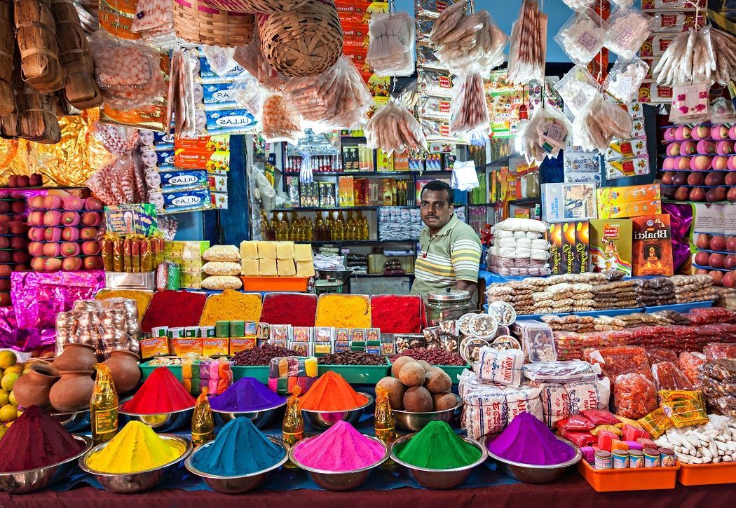 a man stands in front of a display of spices and fruits
