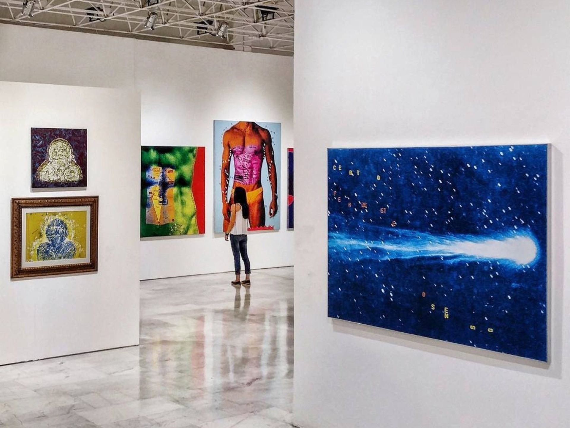 une femme regarde une peinture bleue dans une galerie