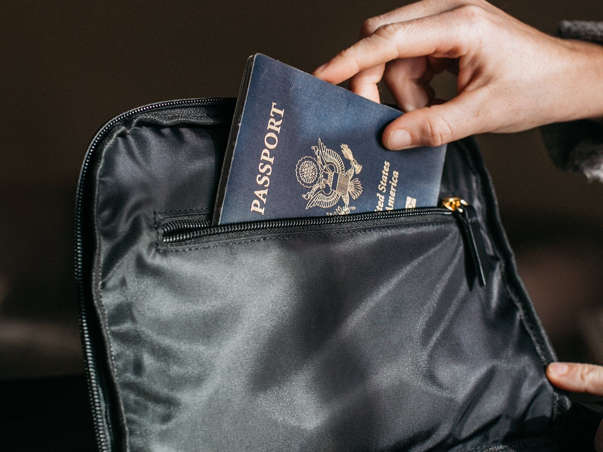 a person is putting a passport into a black bag