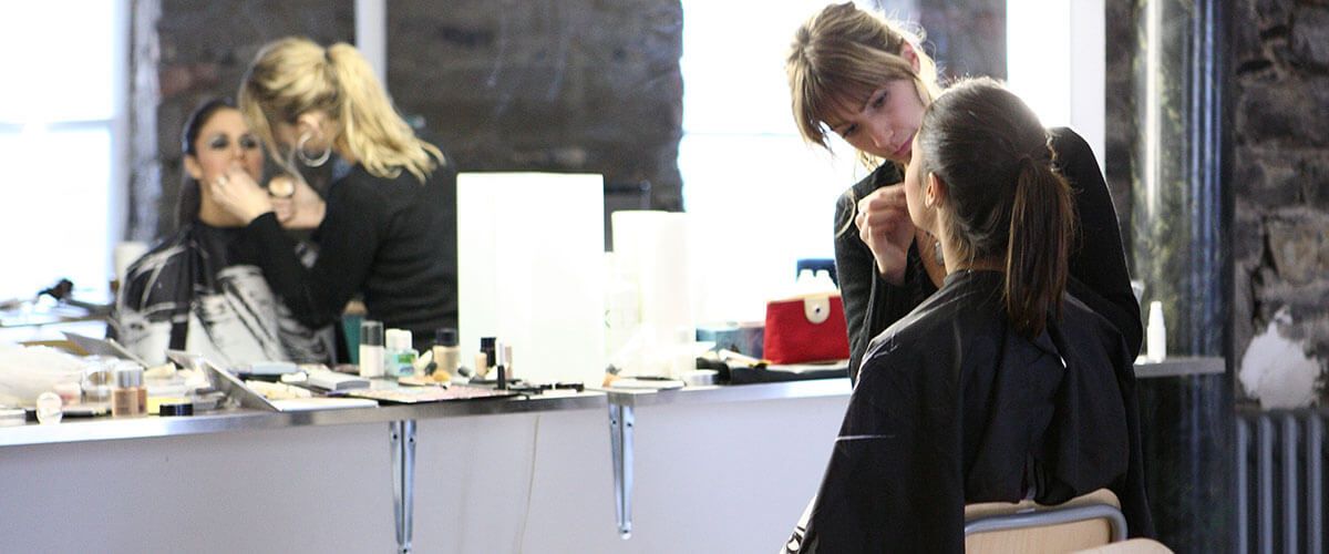 une femme se fait maquiller par un coiffeur dans un salon de beauté