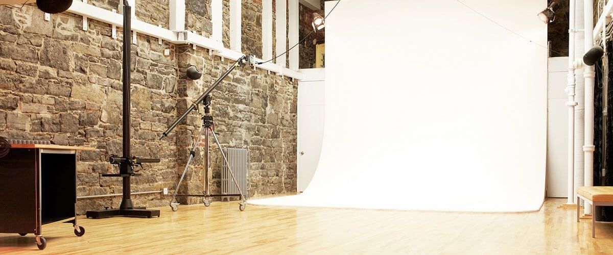 a studio with a white backdrop and a stone wall