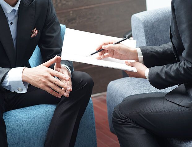 a man in a suit is sitting in a chair talking to another man .