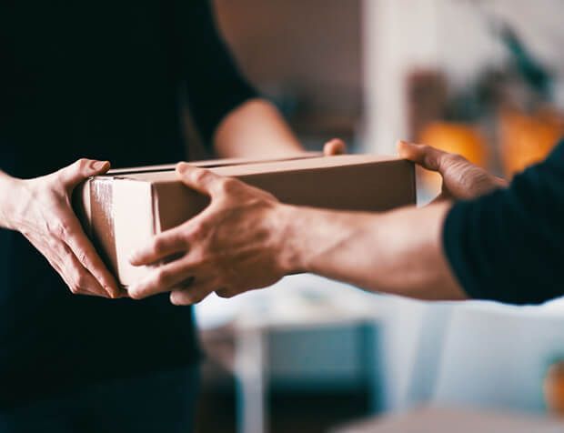 a person is handing a box to another person .