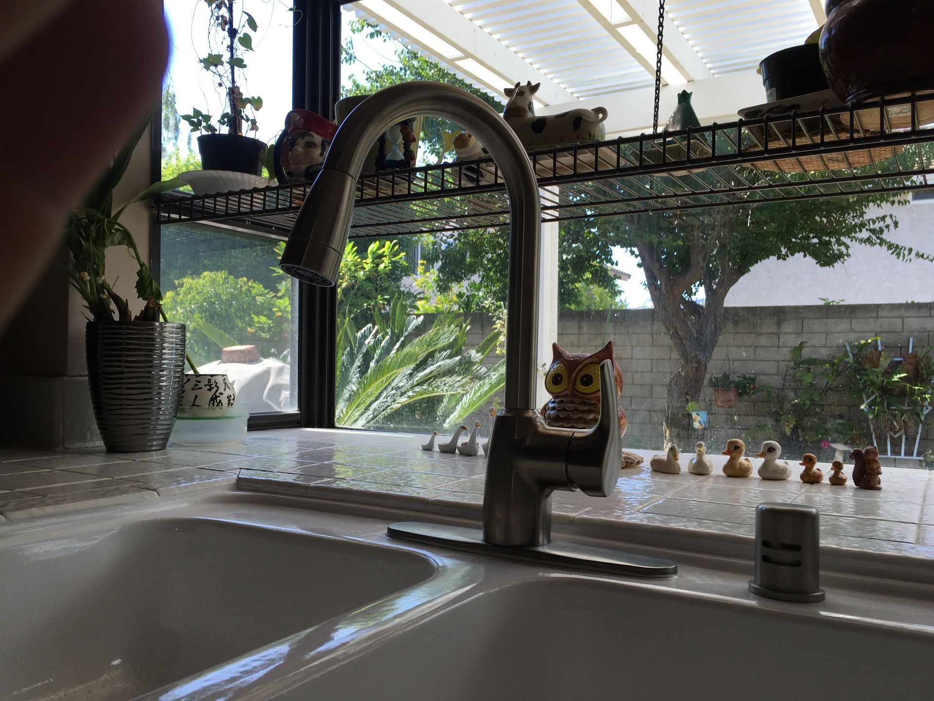 A kitchen sink with an owl figurine on top of it
