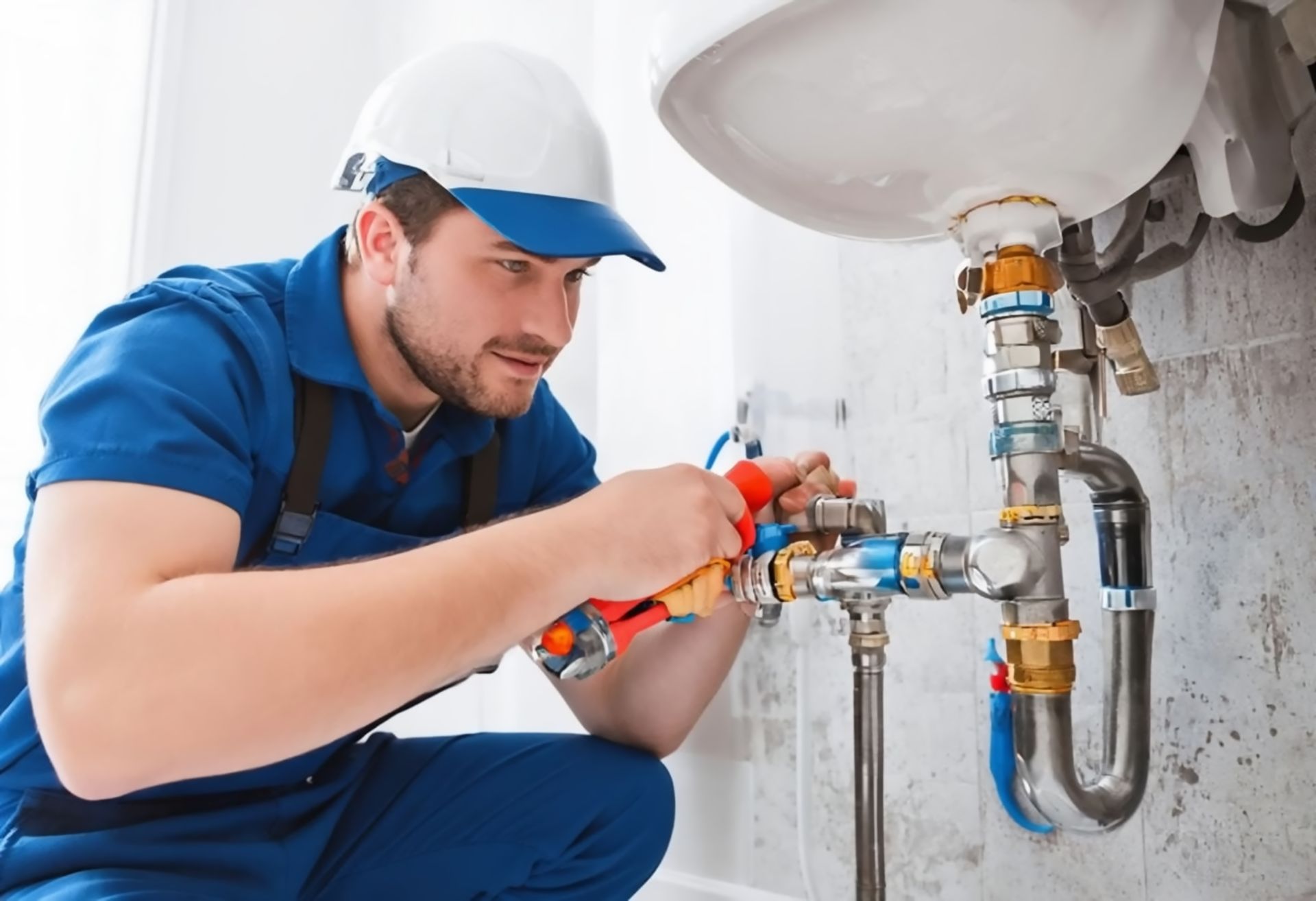 A plumber is fixing a pipe under a sink in a bathroom.