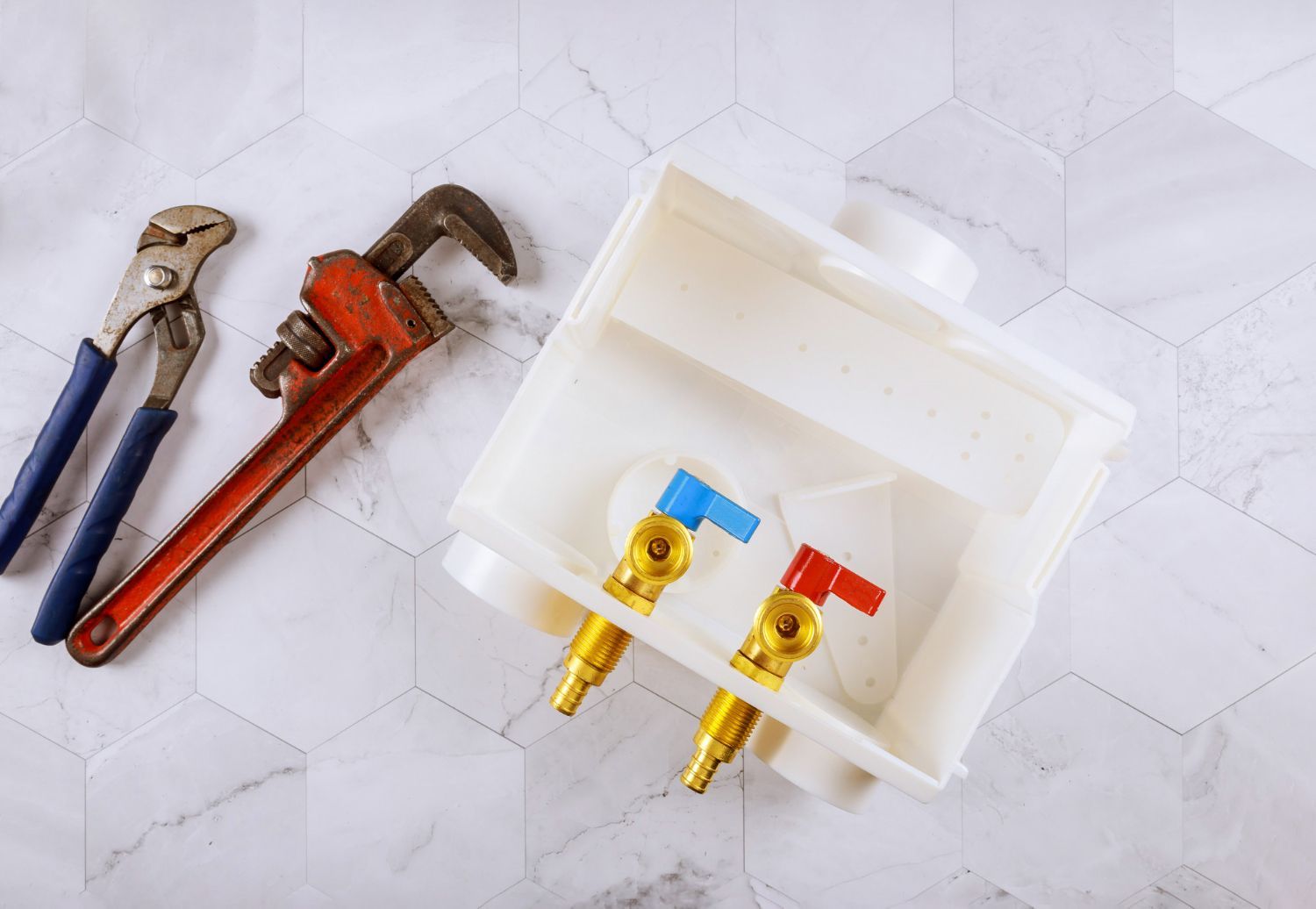 A wrench and pliers are sitting next to a white box on a table.