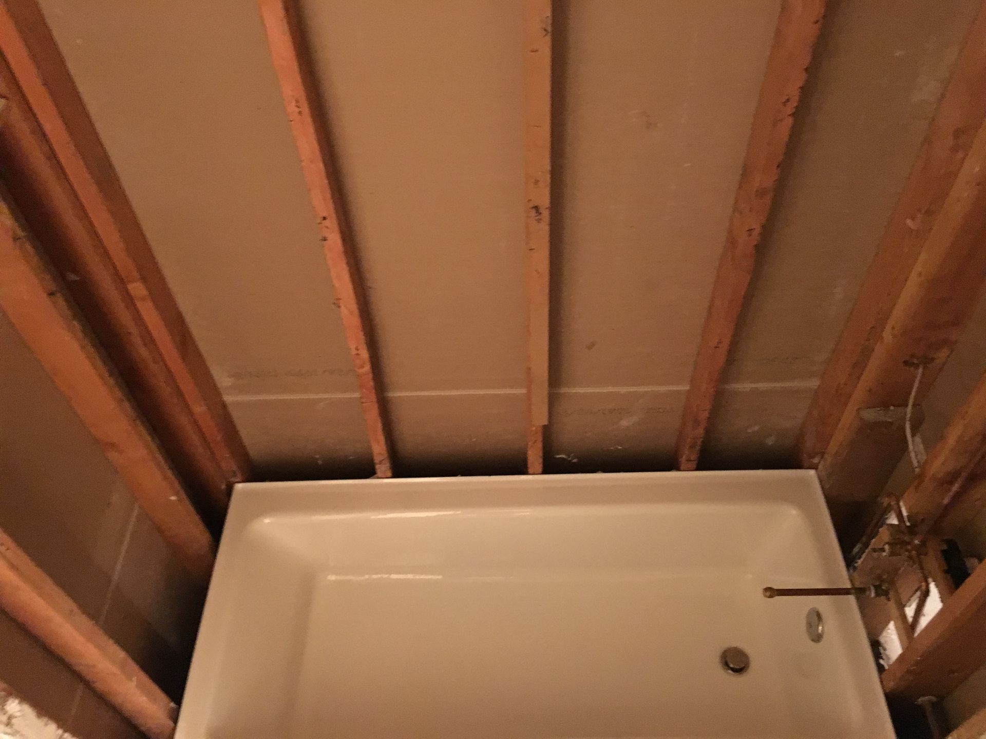 A bathtub is sitting under a wooden ceiling in a bathroom under construction.
