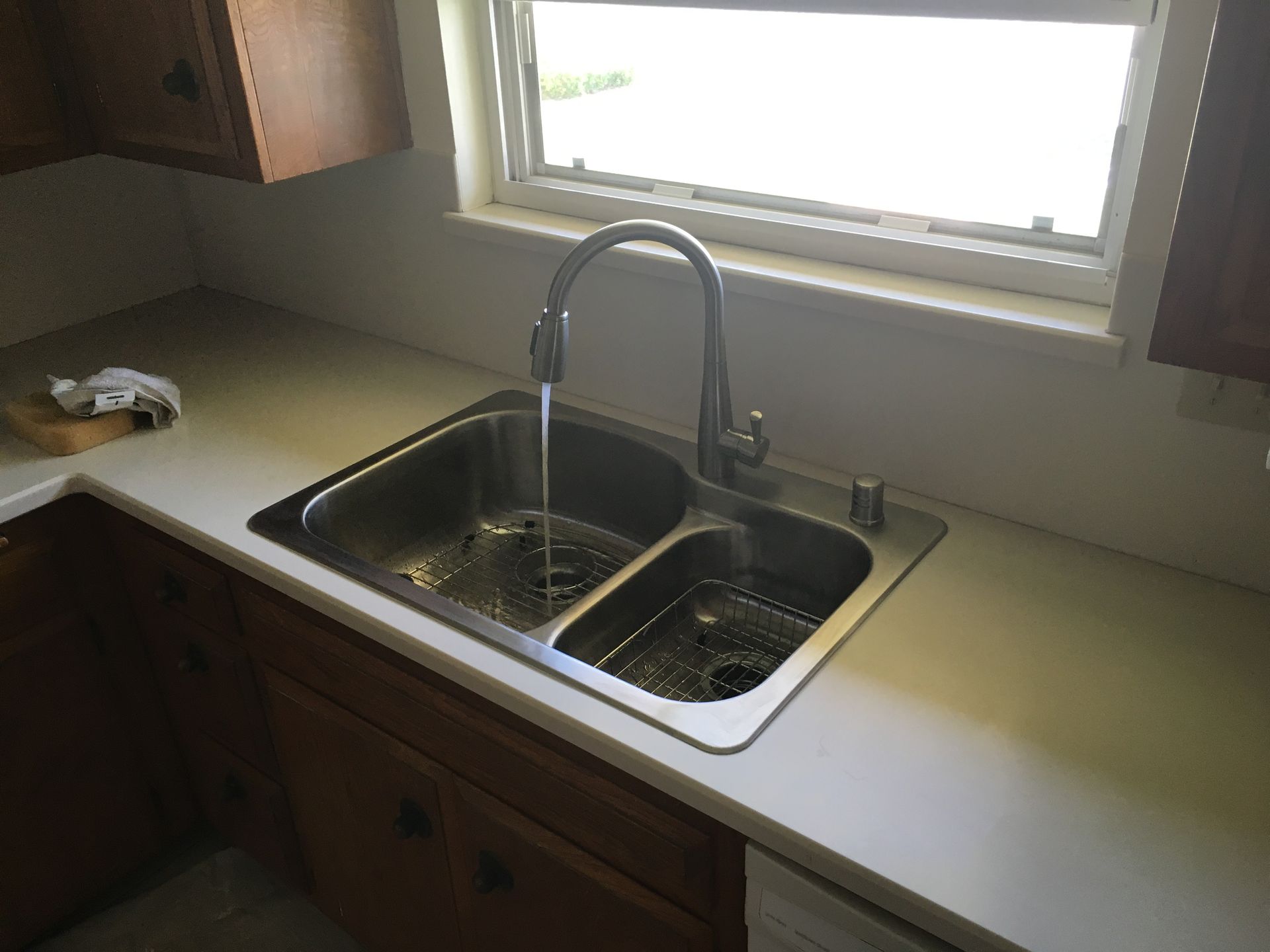 A kitchen sink with water running from the faucet