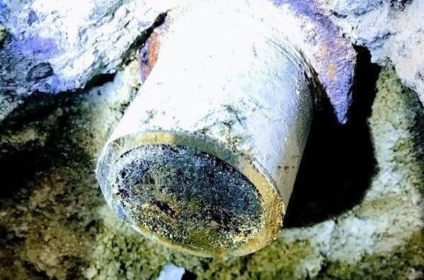 a close up of a rusty pipe in a hole in the ground .