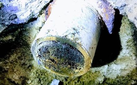 a close up of a rusty pipe in a hole in the ground .