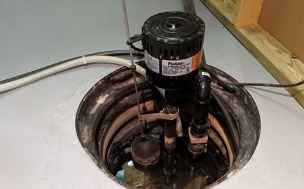 a sump pump is sitting in the corner of a basement .